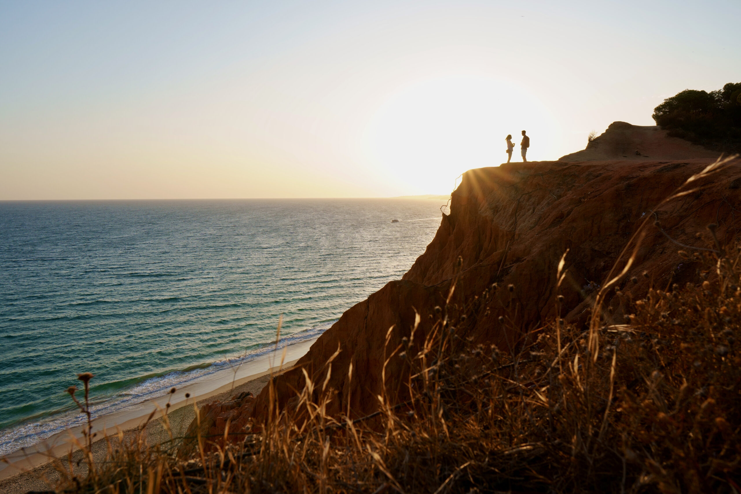 Paar auf Klippe am Meer bei Sonnenuntergang
